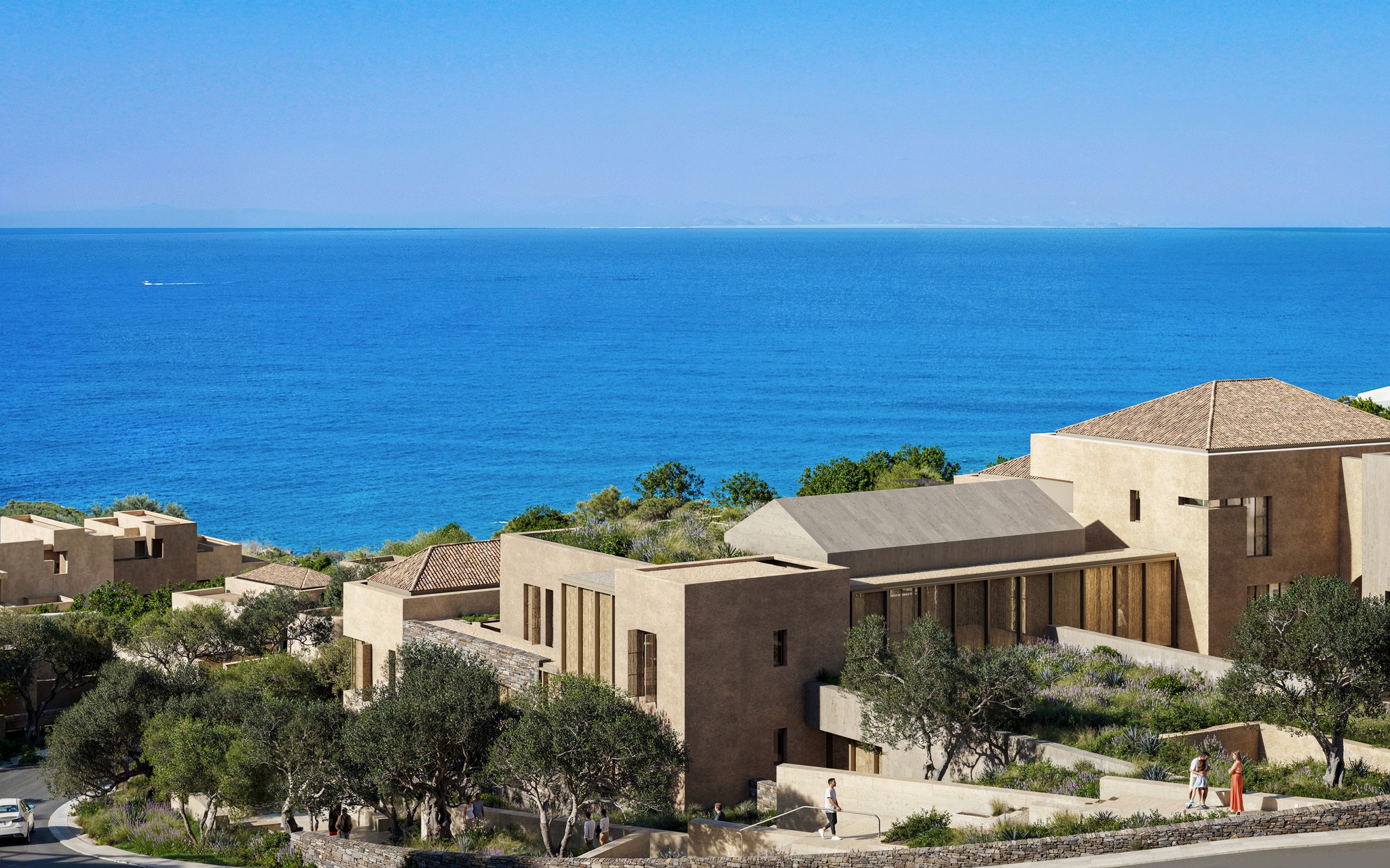 Aerial view of a stone coastal resort overlooking a deep blue sea under a clear sky.